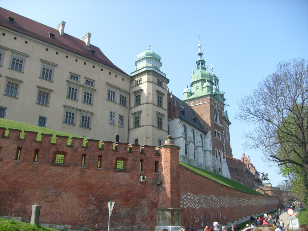 Hrad Wawel stojí na malom kopci, pred ním je červený tehlový múr